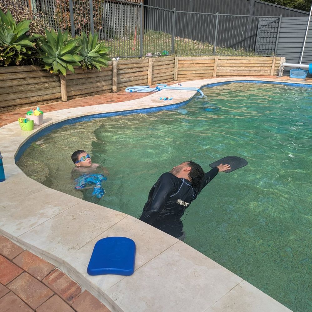 Coach teaching in a sunny backyard pool