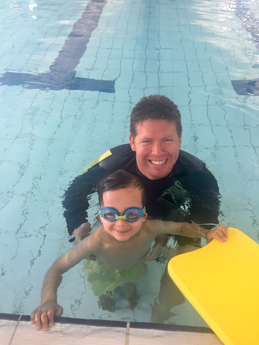 Coach with a young swimmer and kickboard